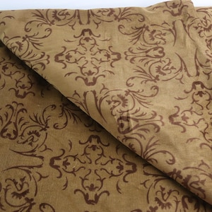 May include: A close-up of a brown fabric with a dark brown floral pattern. The fabric is folded in half, showing the pattern on both sides.