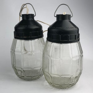 May include: Two clear glass hanging light fixtures with black plastic tops and a wire cord. The glass is textured with a geometric pattern.