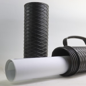 Peut inclure: Tube de rangement cylindrique noir avec une poignée et un motif en losange. Le tube est ouvert à une extrémité et contient un rouleau de papier blanc.