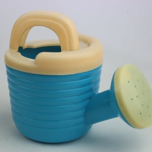May include: A blue plastic watering can with a cream-colored handle and spout. The can has a ribbed design and is perfect for small plants.