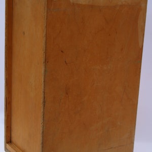 May include: A wooden box with a black handle. The box is made of plywood and has a natural wood finish.