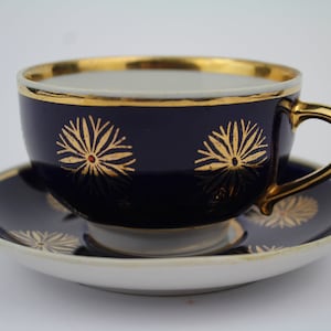以下が含まれることがあります： コバルトブルーのティーカップとソーサーのセット。金色の縁取りと花柄が施されています。カップには金色の取っ手があります。