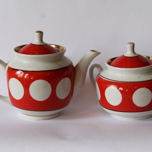 May include: A white teapot and sugar bowl with red and white polka dot designs and gold accents.