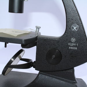 May include: A black microscope with a mirror and a stage. The microscope has a label that reads "УШМ-1 N8008" and a USSR symbol.