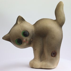 May include: A gray ceramic cat figurine with green eyes. The cat is standing on its hind legs with its tail curled up. The figurine has a small hole on its back.