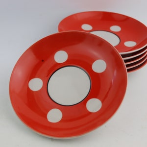 May include: Set of six red and white polka dot ceramic saucers. The saucers have a white center circle with a black outline.