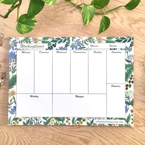Peut inclure: Un planificateur hebdomadaire blanc avec une bordure florale. Le planificateur comporte des sections pour chaque jour de la semaine, ainsi que des sections pour "Wichtig" et "Notizen".