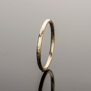 May include: A thin gold band ring with a hammered texture.