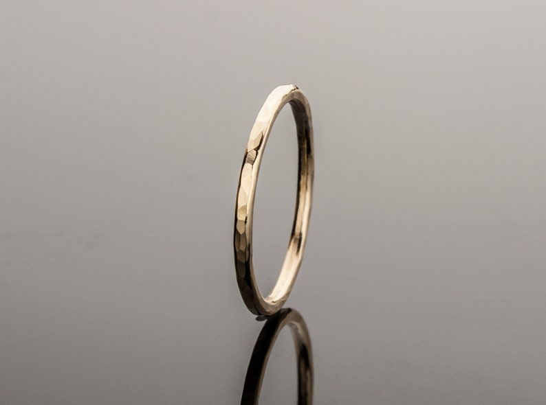May include: A thin gold band ring with a hammered texture.