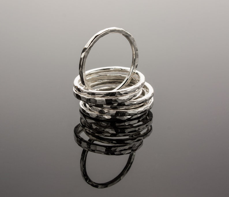 Puede incluir: Una pila de anillos de plata martillados, cada uno con un ancho y una textura ligeramente diferentes. Los anillos est&aacute;n dispuestos en un patr&oacute;n circular, con el anillo m&aacute;s grande en la parte inferior y el anillo m&aacute;s peque&ntilde;o en la parte superior.