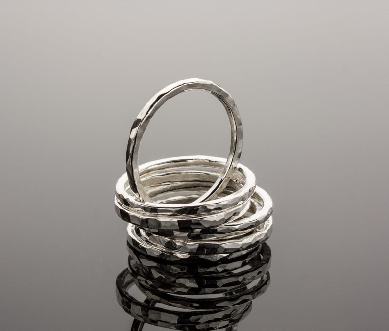 Puede incluir: Una pila de ocho anillos de plata martillados. Los anillos est&aacute;n apilados uno encima del otro, siendo el anillo superior el m&aacute;s grande y el anillo inferior el m&aacute;s peque&ntilde;o.