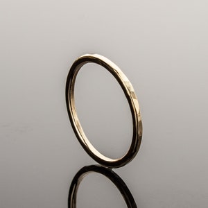 May include: A simple gold band ring with a hammered finish.