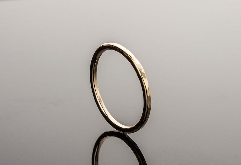 May include: A simple gold band ring with a hammered finish.
