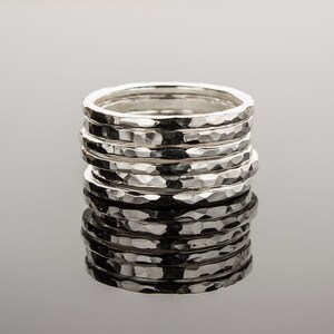 Puede incluir: Una pila de seis anillos de plata martillados. Los anillos est&aacute;n apilados uno encima del otro y todos son del mismo tama&ntilde;o. Los anillos est&aacute;n hechos de un metal liso y brillante.