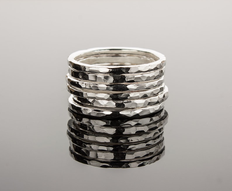 Puede incluir: Una pila de seis anillos de plata martillados. Los anillos est&aacute;n apilados uno encima del otro y todos son del mismo tama&ntilde;o. Los anillos est&aacute;n hechos de un metal liso y brillante.