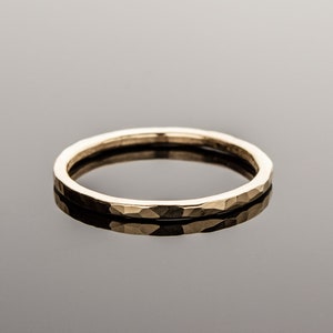 May include: A simple gold band ring with a hammered texture.
