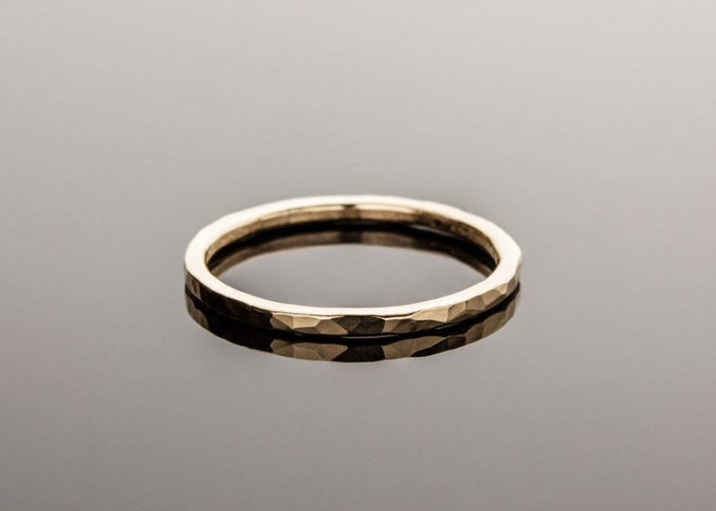 May include: A simple gold band ring with a hammered texture.