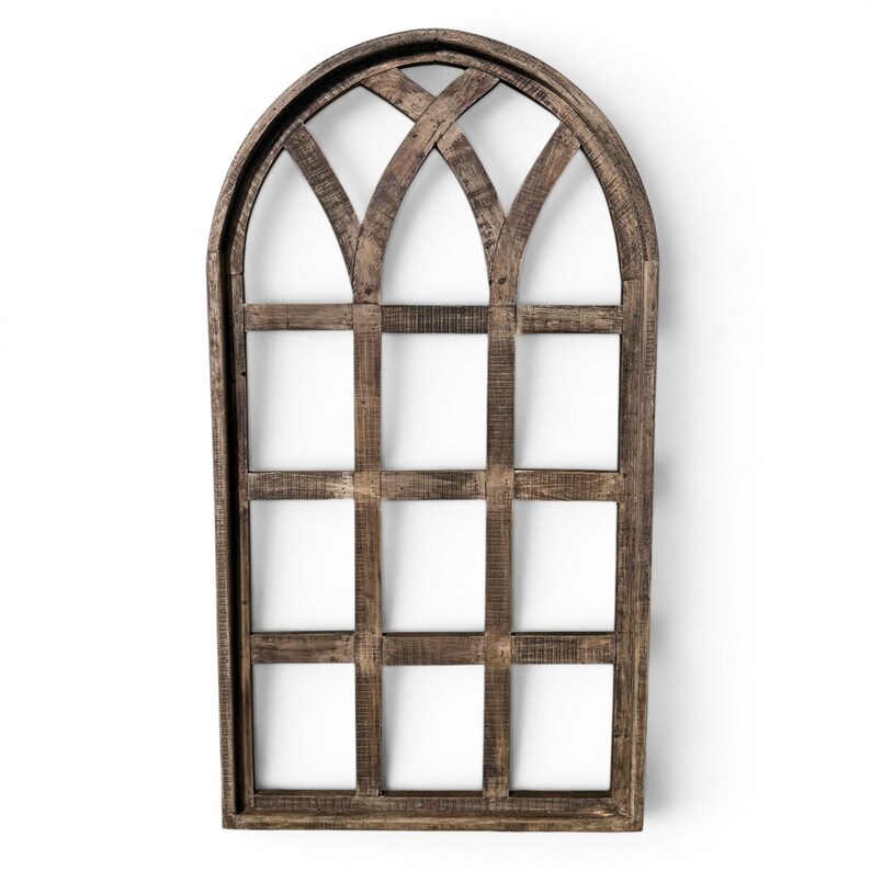 May include: A decorative wooden window frame with an arched top and a grid pattern. The frame is made of weathered brown wood, and the grid sections are open, revealing a white background. This rustic wall decor adds a farmhouse touch.