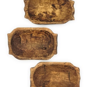 May include: Three rustic wooden dough bowls of varying sizes. The bowls are made of natural wood and have a warm brown color. They are perfect for serving bread, fruit, or other snacks.