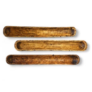 May include: Three wooden bread bowls, also known as dough bowls, are stacked on top of each other. The bowls are made of natural wood and have a rustic, farmhouse style.