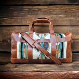 May include: A brown leather duffel bag with a woven pattern in shades of blue, green, and orange. The bag has a long strap and a top handle.