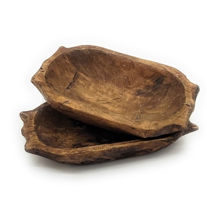 May include: Two rustic wooden bowls, one stacked on top of the other, with a natural brown finish. The bowls are oval shaped and have a slightly rough texture.