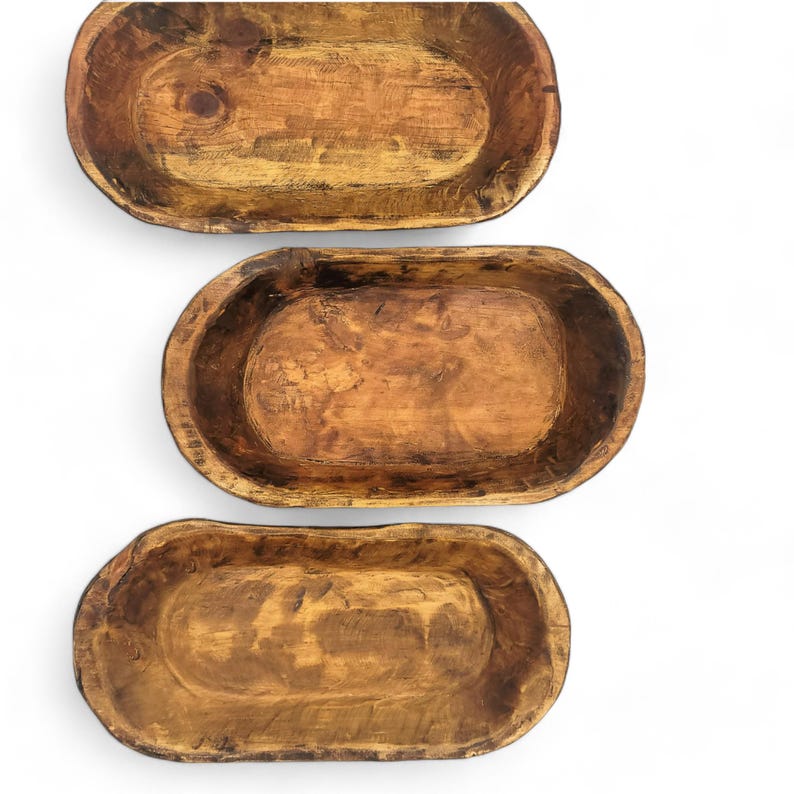 May include: Three wooden dough bowls of varying sizes. The bowls are oval shaped and have a rustic, natural finish.