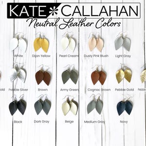 May include: A variety of leather earrings in different colors and textures, including white, yellow, cream, pink, gray, brown, green, gold, and champagne. The earrings are arranged in rows on a white wooden surface. The text "KATE CALLAHAN Neutral Leather Colors" is displayed at the top of the image.