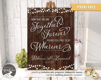May include: Printable wedding sign with a rustic wood background and white lights. The sign says "Now that we are together forever, please feel free to sit wherever."  Rebecca and Leonard 10.21.2017.