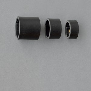 May include: Three black leather rings of different sizes. The rings are made of a smooth, supple leather and have a simple, elegant design.