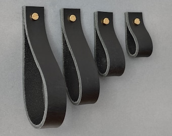 May include: Four black leather cabinet pulls with brass screws. The pulls are in different sizes, with the largest pull on the left and the smallest pull on the right.
