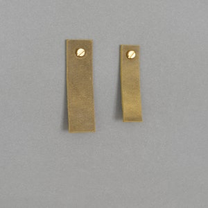 May include: Two rectangular leather straps with brass screw accents. The straps are different sizes.
