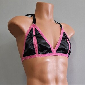 May include: A black satin bralette with pink lace trim and a bow detail. The bralette has adjustable straps and a hook and eye closure.