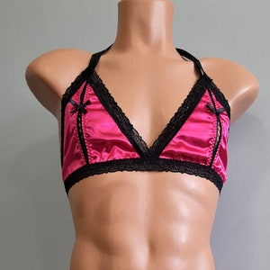 May include: A pink satin triangle bra with black lace trim and black satin bows on the straps.