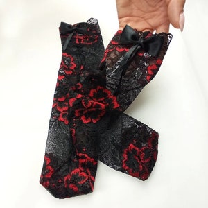May include: A pair of black lace socks with red floral embroidery and black bows at the top.