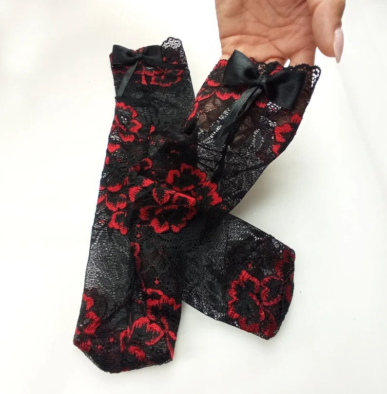 May include: A pair of black lace socks with red floral embroidery and black bows at the top.