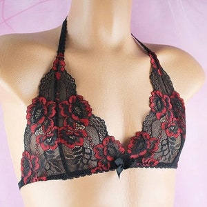 May include: Black lace bralette with red floral embroidery. The bralette has a halter style strap and a bow detail at the center.