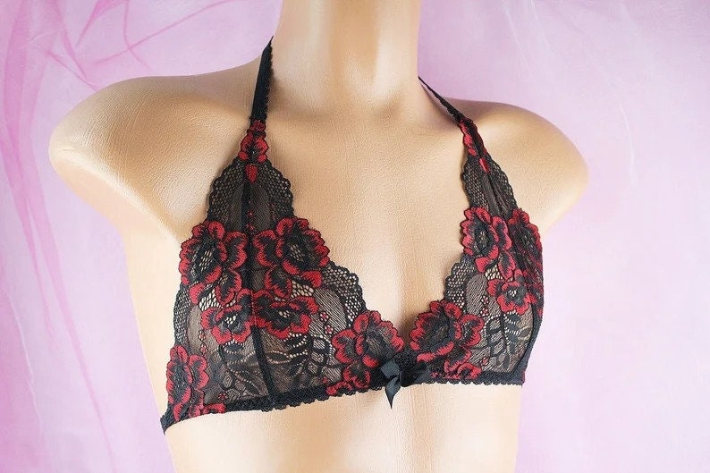 May include: Black lace bralette with red floral embroidery. The bralette has a halter style strap and a bow detail at the center.