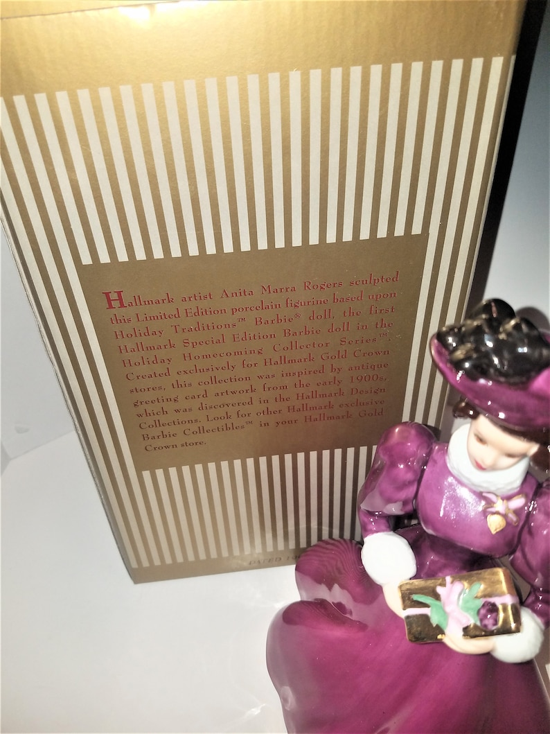 May include: A porcelain figurine of a woman in a purple dress holding a gift box. The figurine is based on the first Hallmark Special Edition Barbie doll in the Holiday Homecoming Collector Series. Hallmark artist Anita Marra Rogers sculpted this figurine.