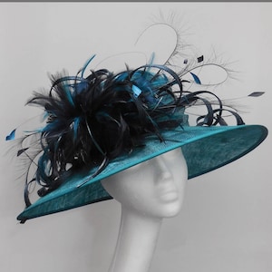 May include: A teal blue wide-brimmed hat with a black feather trim. The hat is decorated with a large black feather plume and smaller black feathers.