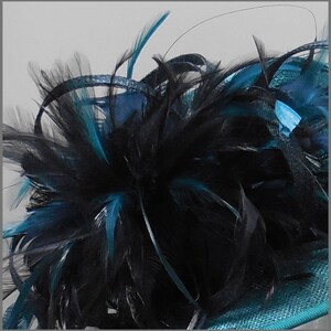 May include: A teal blue hat with a black and teal feather trim.