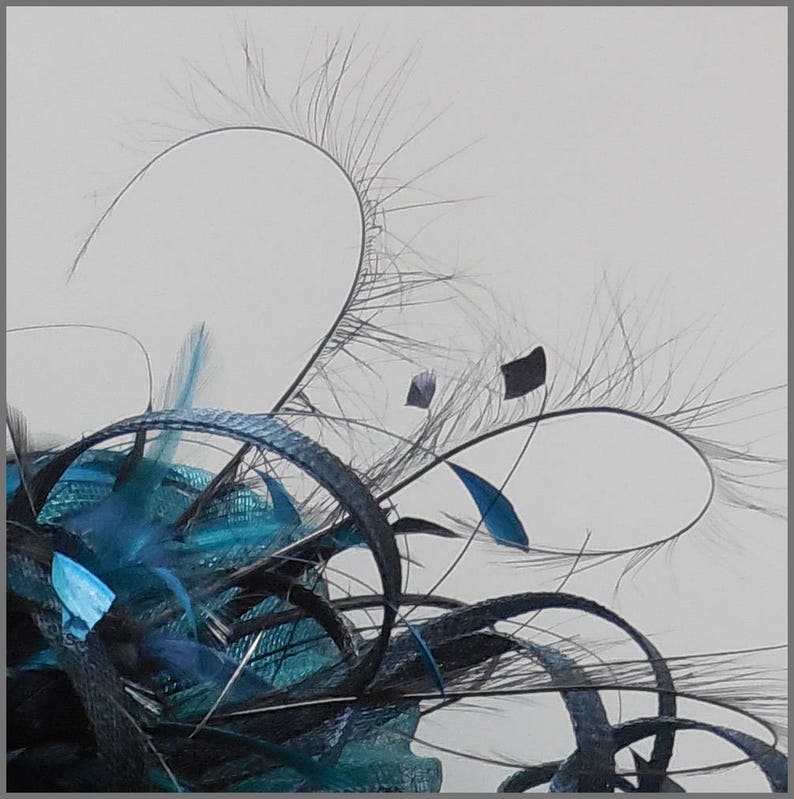 May include: A teal blue and black feather fascinator with a delicate, wispy design. The feathers are arranged in a circular pattern, creating a soft and elegant look.