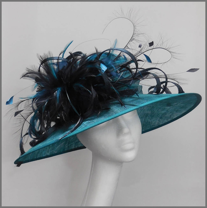 May include: A teal blue wide-brimmed hat with a black feather trim. The hat is decorated with a large black feather plume and smaller black feathers.