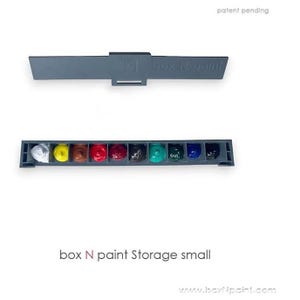May include: A gray plastic paint storage box with the text "box N paint" on the lid. The box has 10 compartments filled with different colors of paint, including white, yellow, brown, red, dark red, black, green, blue, and dark blue.