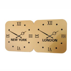 Könnte beinhalten: Eine goldfarbene Wanduhr mit zwei quadratischen Zifferblättern. Das linke Zifferblatt zeigt "NEW YORK" und das rechte Zifferblatt zeigt "LONDON". Beide Zifferblätter haben römische Ziffern als Stundenmarkierungen und schwarze Zeiger.