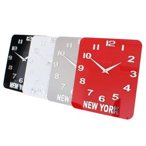 Può includere: Quattro orologi quadrati con quadranti nero, bianco, grigio e rosso. Ogni orologio ha numeri neri e una lancetta argentata. Tutti gli orologi riportano la scritta "NEW YORK" in basso.