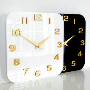 May include: Two square clocks with gold hands and numbers. One clock has a white face and the other has a black face.