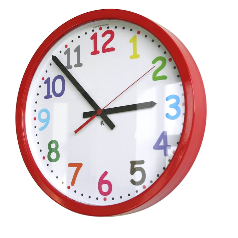 May include: A red round clock with colorful numbers and black hands. The clock face is white with black dots around the edge. The numbers are in different colors: 12 is red, 1 is yellow, 2 is green, 3 is blue, 4 is purple, 5 is gray, 6 is orange, 7 is orange, 8 is green, 9 is blue, 10 is purple, and 11 is gray.