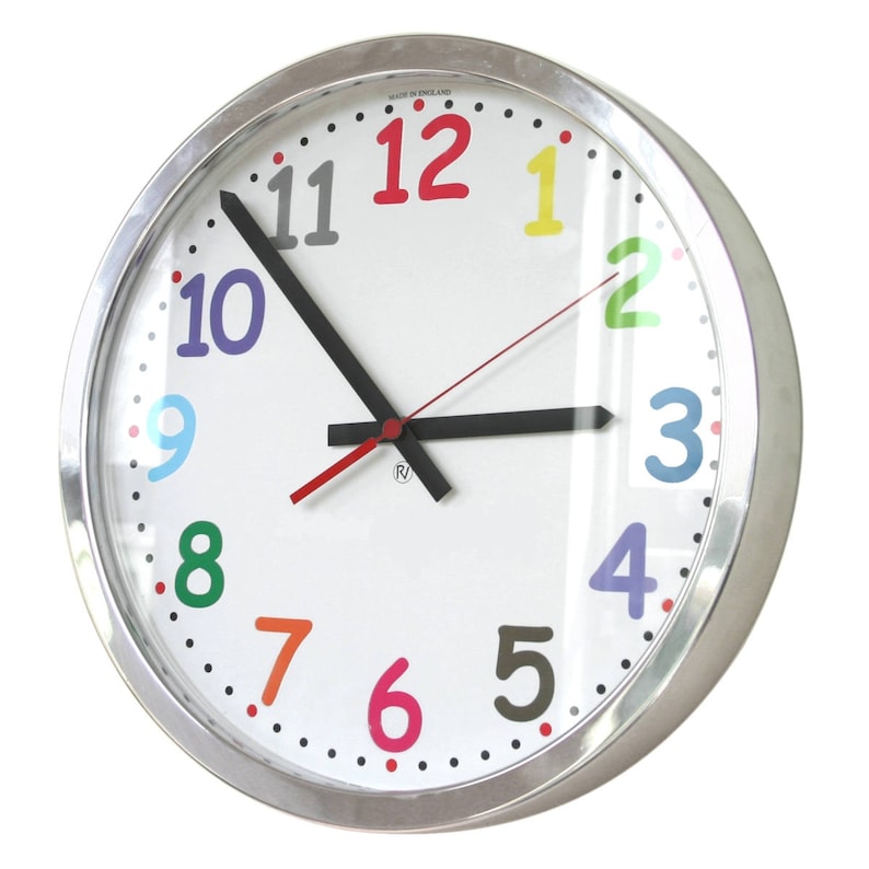 May include: A silver framed clock with a white face and colorful numbers. The numbers are in a rainbow pattern, with red at the top and purple at the bottom. The clock hands are black and red.