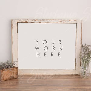 May include: White distressed wood frame with a white mat and the text "YOUR WORK HERE" on a white background. The frame is sitting on a wooden table with a small wooden box and a vase of dried flowers.